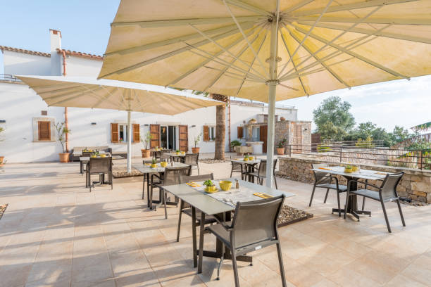 Outdoor patio with open umbrellas over dining tables at a sunny restaurant.