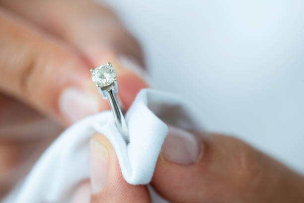 Person cleaning a diamond ring with a white cloth, demonstrating a homemade jewelry cleaning method.