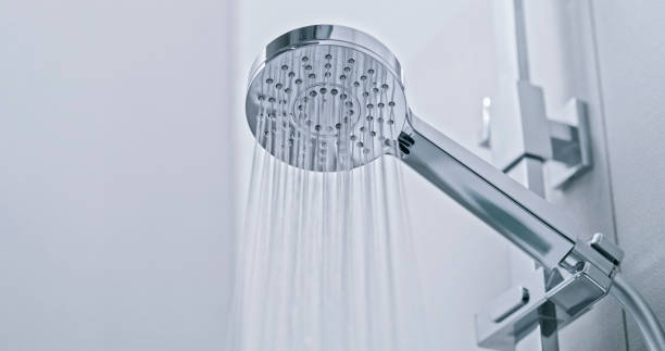 A chrome showerhead streaming water, illustrating effective cleaning tips using basic pantry ingredients.